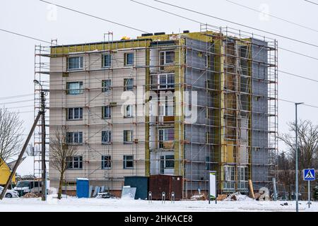 Scaffolding on multi storey building facade during renovation. Exterior passive house wall heat insulation with mineral wool. Insulation facade of mul Stock Photo