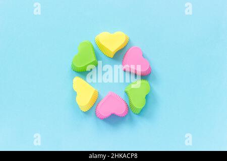 Colored silicone heart shaped molds dish for baking cupcakes on blue paper background. Template for lettering, text or your design Top view, copy spac Stock Photo