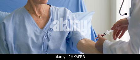 Doctor collects blood sample from elderly patient. Coronavirus disease 2019 testing process in a hospital. Stock Photo