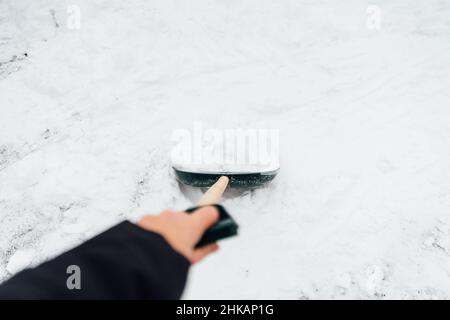 Close up of big iron shovel in the process of removing the snow in winter. Unrecognizable human holding shovel with his hand Stock Photo