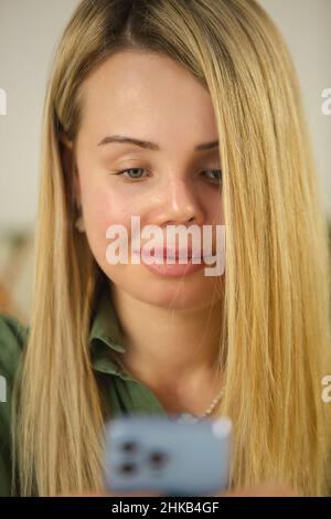 Abuse victim portrait. Young woman with prosthetic eye and face scars using modern mobile phone for communication online during lockdown. Beautiful do Stock Photo