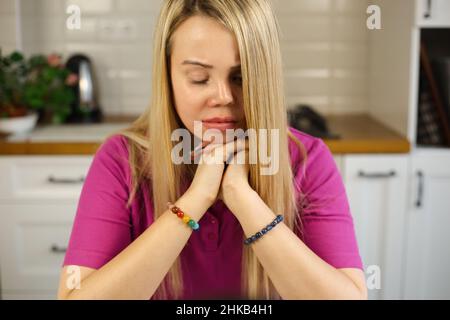 Sad young woman with face scars  thinking about future. Stressed and tired female with facial scar and prosthetic eye sitting at home with closed eyes Stock Photo