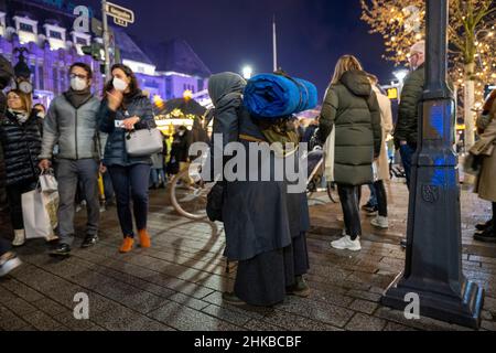 shoppers pass by a woman begging for money on Königsallee in the city centre of Düsseldorf, NRW, Germany on 11.12.2021 Stock Photo