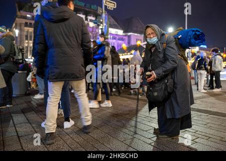shoppers pass by a woman begging for money on Königsallee in the city centre of Düsseldorf, NRW, Germany on 11.12.2021 Stock Photo