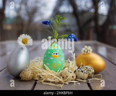 Souvenir egg with a cute painted chick is decorated with natural spring flowers. creative ideas for decor. happy easter holiday. Festive spring atmosp Stock Photo