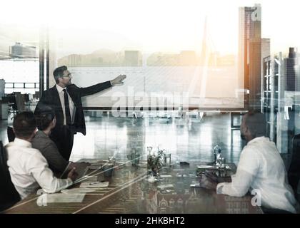 Projecting profits. Multiple exposure shot of businesspeople in a meeting superimposed on a cityscape. Stock Photo