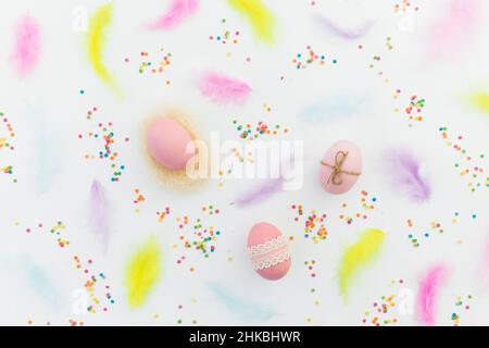 Ester composition with eggs, feathers and confetti on white background. Flat lay, top view Stock Photo
