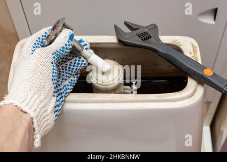 hand dismantling the flush mechanism of the toilet tank Stock Photo