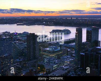 A dramatic shot of a cruise leaving the harbour during a violet sunset on the Hudson River in Manhattan in New York City Stock Photo