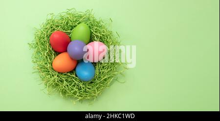 Easter, Spring Holiday celebration, Pastel color paint egg in a nest, green background, top view, copy space. Stock Photo