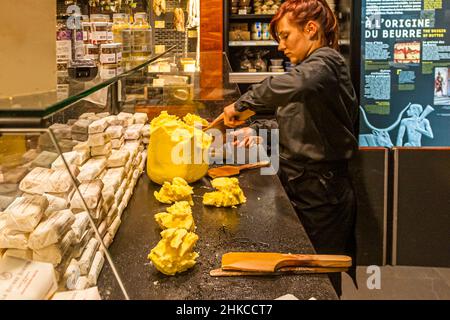 At the Maison du Beurre in Saint Malo, the saleswoman cuts pieces of 125 g from a block of butter. Maison du Beurre Bordier, Saint-Malo, France Stock Photo