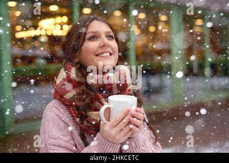 pretty girl watching snow fall and drinking coffee or hot chocolate with marshmallows Stock Photo