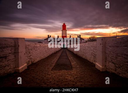 The cobbled pathway to the red and white striped, 23 meter tall,  Souter Lighthouse in Marsden, South Shields as the sun rises Stock Photo