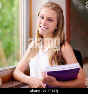 School is awesome. Shot of a young girl in her school hallway. Stock Photo