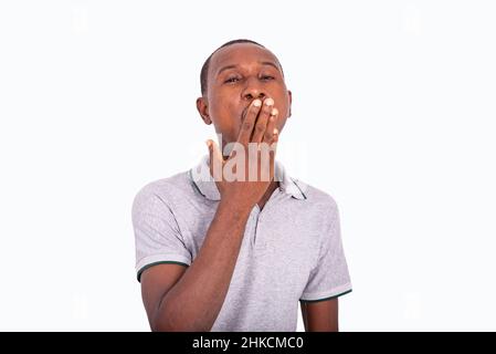 tired young man yawning with hand over mouth. isolated on white background. Stock Photo