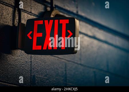 glowing exit sign by night on black wall Stock Photo