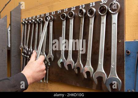 Auto car mechanic taking wrench working tools in automobile at repair service. Garage craft concept. Stock Photo