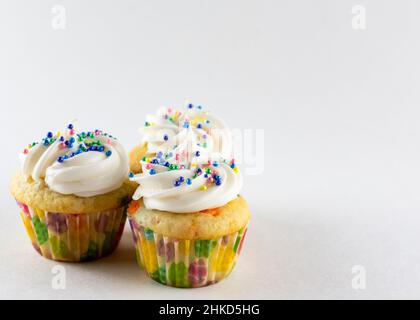 Three mini confetti cupcakes on a white background with white background.  Decorated with Easter sprinkles.  Copy space. Stock Photo