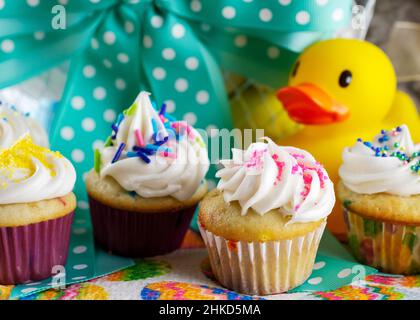 A close up view of assorted mini cupcakes with Easter basket in background. Stock Photo