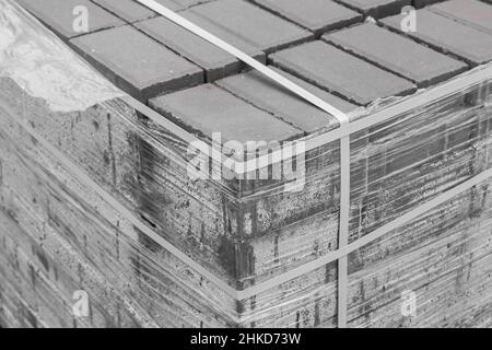 Stone pavement blocks in a pile of tiles building material packed in polyethylene film on construction site. Stock Photo