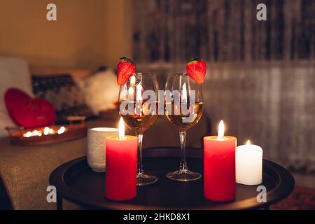 Valentines day celebration at home with champagne wine glasses with strawberries on top surrounded with candles Stock Photo