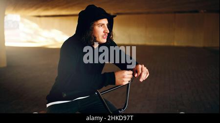 Mind full of tricks. Cropped shot of a young man chilling on his BMX in an underground parking lot. Stock Photo