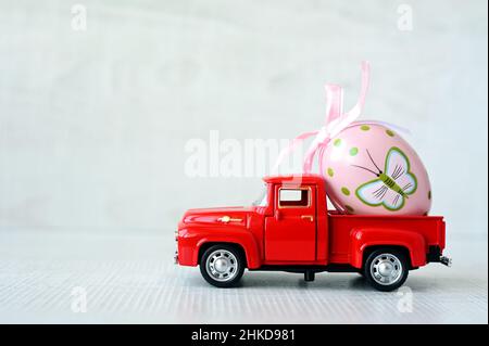 One Easter egg on a small car on a grey background. Copy space. Easter card. Stock Photo