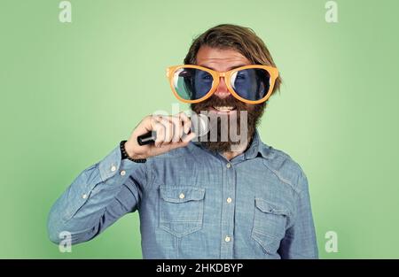 Music is only love looking for words. performer having fun. mature bearded man in funny party glasses sing song. brutal male hipster with microphone Stock Photo