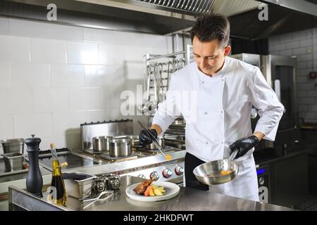 Chef Preparing Dish In Kitchen. Decorating Dish Stock Photo