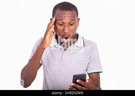 young surprised man with open mouth holding and looking on mobile phone. Stock Photo