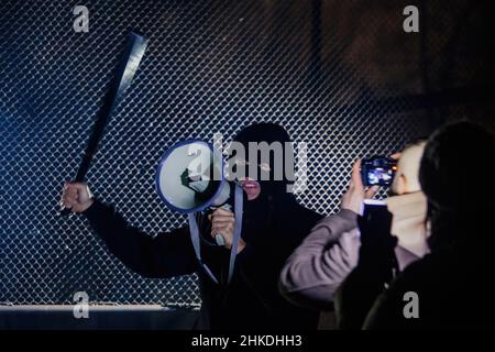 Masked rebel with bat and megaphone. Journalists are making pictires Stock Photo
