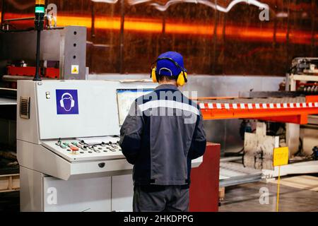 Factory worker operating CNC machine in metalworking workshop. Stock Photo