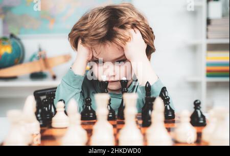 Boy think or plan about chess game, vintage style for education concept. Child and childhood. Clever concentrated and thinking child while playing Stock Photo