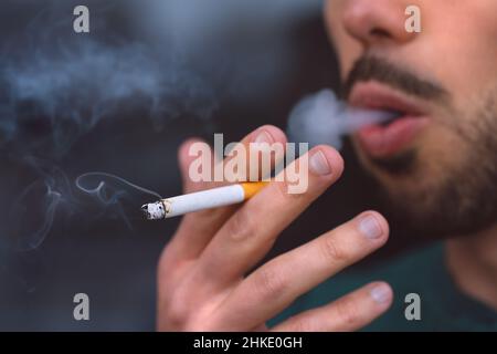 Closeup of young man smoking cigarette. Smoking addiction and bad habit concept Stock Photo