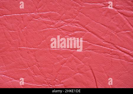 Fragment of genuine leather with wrinkles and folds, artificially dyed bright red. Background, pattern, texture. Stock Photo