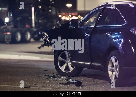 Traffic Accident Automotive Collision at Night. Heavy Damaged Modern Car on a Street. Transportation Safety Theme. Car Crash. Stock Photo