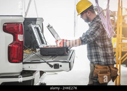 Caucasian Construction Worker Reading HVAC Assembly Plan and Documentation on a Site Next to His Modern Pickup Truck. Stock Photo