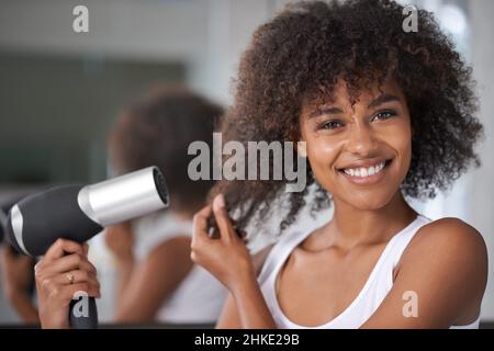 Blowing out my hair. Shot of an attractive young woman taking care of her hair. Stock Photo