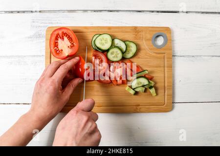 Woman's hands cut tomatoes and cucumbers. fresh food and vitamins. Stock Photo