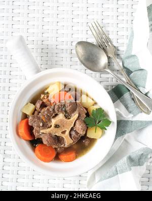 Sop Buntut or Oxtail Soup Served in White Bowl on White Woven Table. Top View Stock Photo