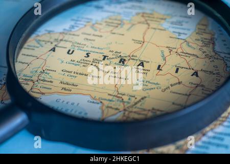 Australia on a world map through magnifying glass. Australia travel destination planning pinned Stock Photo