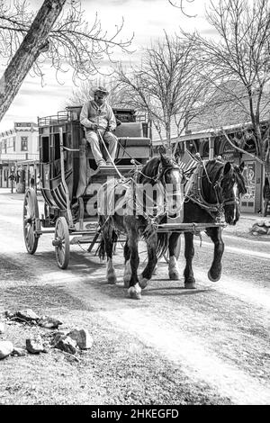 A black and white photograph of a stage couch rolling down the main street of the town of Tombstone, Arizona, USA. Stock Photo