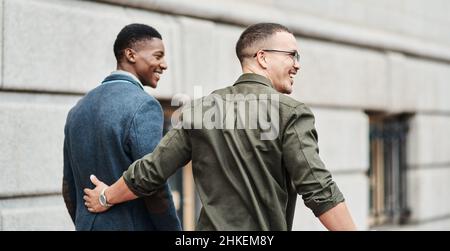 Taking this journey to success together. Rearview shot of two young businessmen walking through the city together. Stock Photo