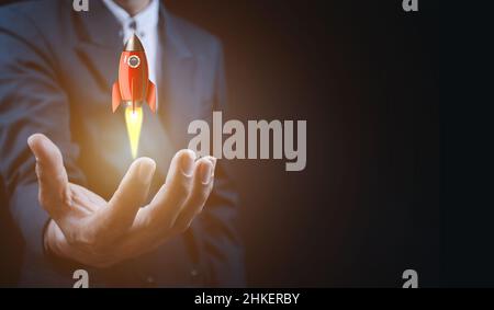 Male hand holding rocket icon that takes off,  rocket is launching and flying out, Business start up, Icon marketing on modern virtual interface.Start Stock Photo