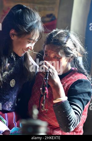 (220204) -- LHASA, Feb. 4, 2022 (Xinhua) -- Tenzin Drolma (L) hands a cup of buttered tea to her mother at home in Gyaga Village of Damxung County, southwest China's Tibet Autonomous Region, Jan. 18, 2022. Tenzin Drolma, 21, was born on the grassland near Lake Namtso in Tibet. In 2020, she was admitted to Jiangsu Food and Pharmaceutical Science College in east China's Jiangsu Province as a Chinese pharmacy major student. The college life in the outside world is fresh to Drolma. She met many new classmates and made many friends. When winter vacation came, Drolma returned to her beloved ho Stock Photo