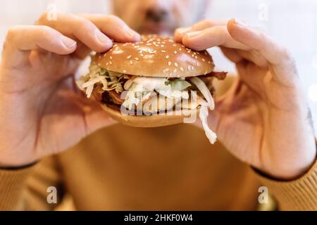 A man eats a burger with meat in a cafe. Fast food, junk food, fast carbs, obesity, overeating, stress concept. High quality photo Stock Photo
