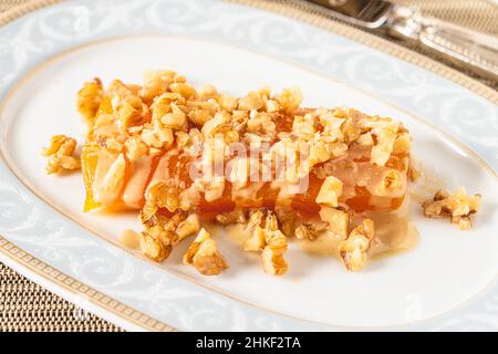 Pumpkin dessert with tahini and walnuts on a white porcelain plate Stock Photo