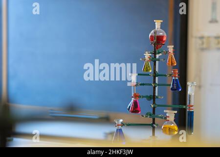School chemistry laboratory. Various colored solutions into flask with blackboard in the background. Stock Photo