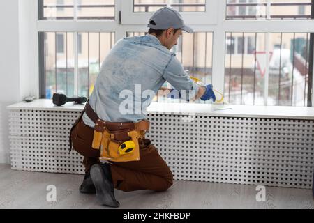 Construction worker putting sealing foam tape on window in house Stock Photo