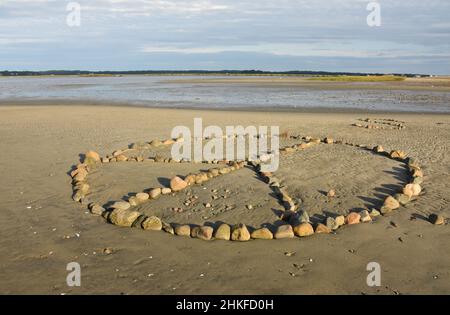 Stunning design of a peace symbol on a beach made of rocks. Stock Photo